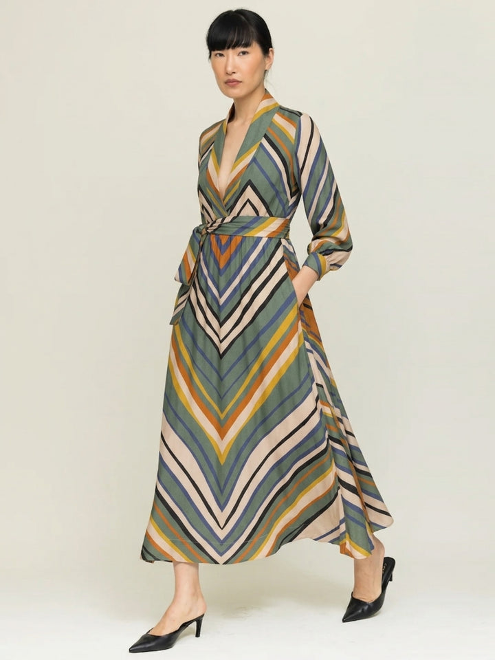 model wearing stripe print wrap dress with  hands in pockets against a neutral background 